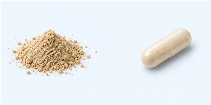 Botanical powder beside a supplement capsule